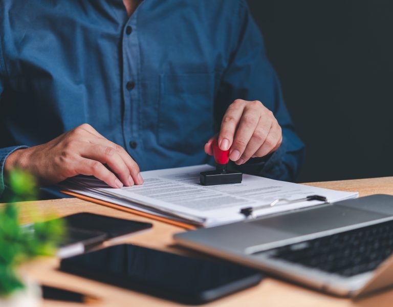 A person's hands are seen stamping a document
