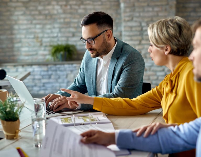 Real estate agent using laptop while having a meeting with a couple in the office.